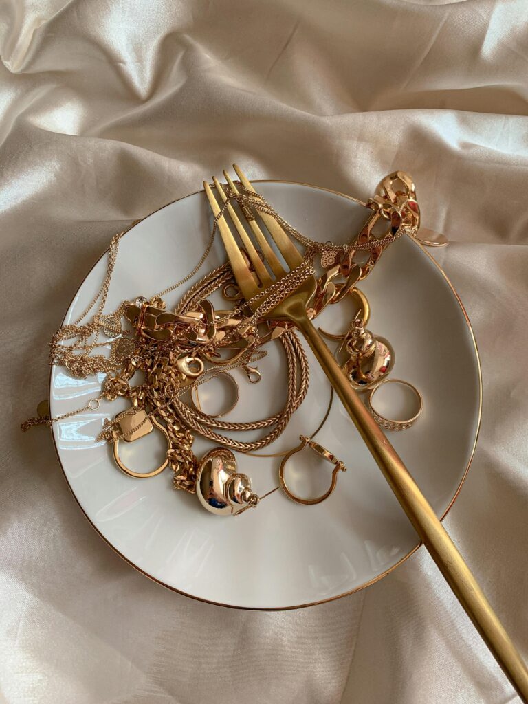 Image of a collection of jewellery in a saucer plate with a golden fork