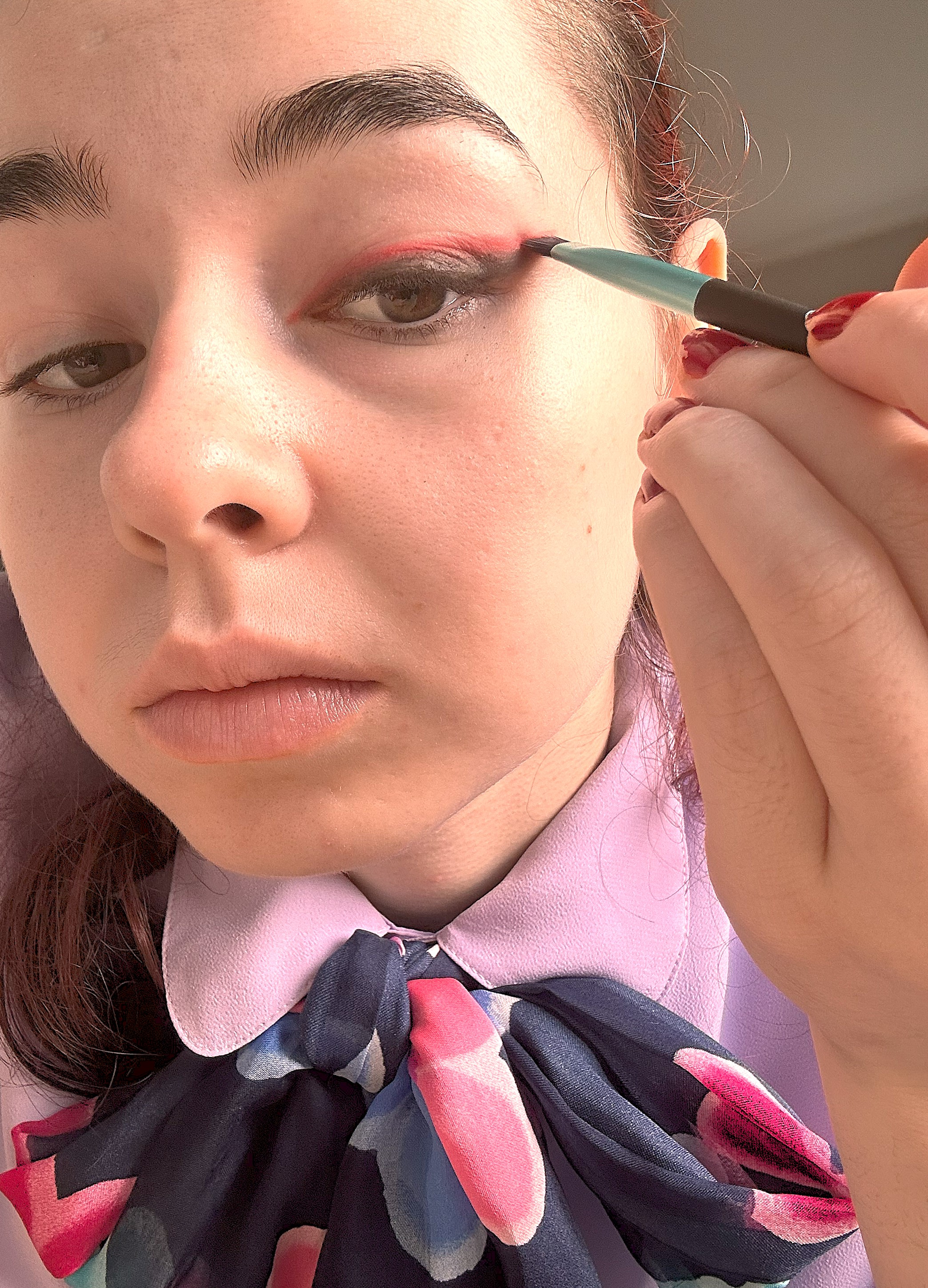 Applying red eyeshadow on top of the black eyeliner cat eye